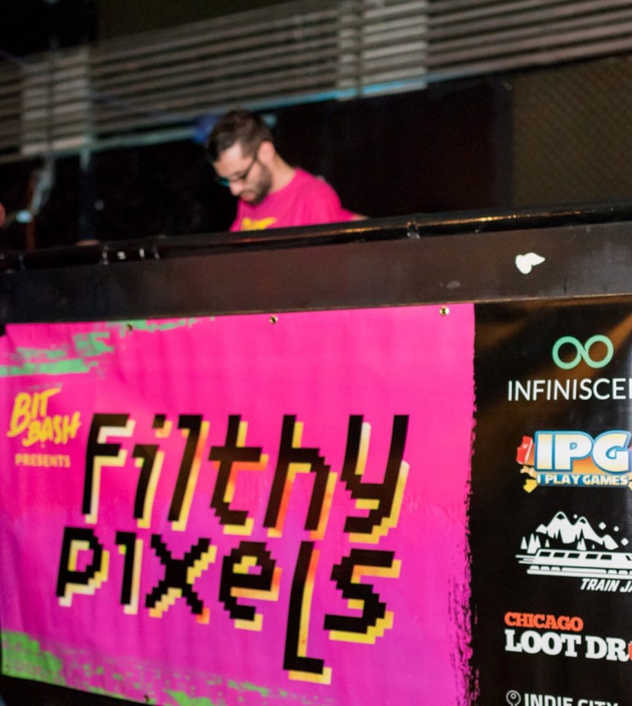 Loud grungy magenta vinyl banner for Bit Bash’s “Filthy Pixels” party, in front of the DJ booth